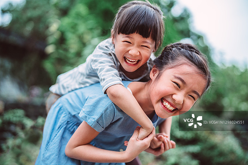 女孩在公园背着妹妹图片素材