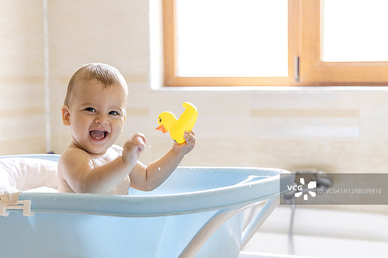 一个可爱的婴儿正在浴缸里洗澡，一个在洗澡时泼水的婴儿图片素材
