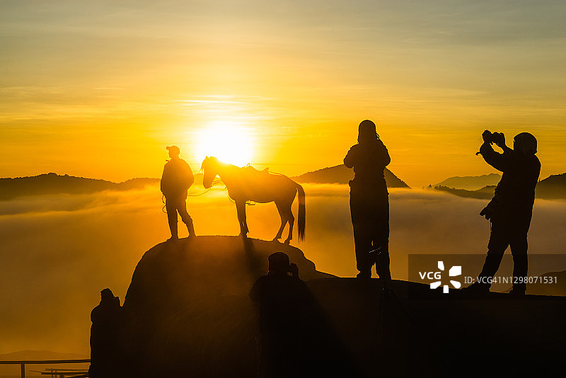 在布罗莫火山山腰，身份不明的游客拍摄雄伟日出的轮廓图片素材