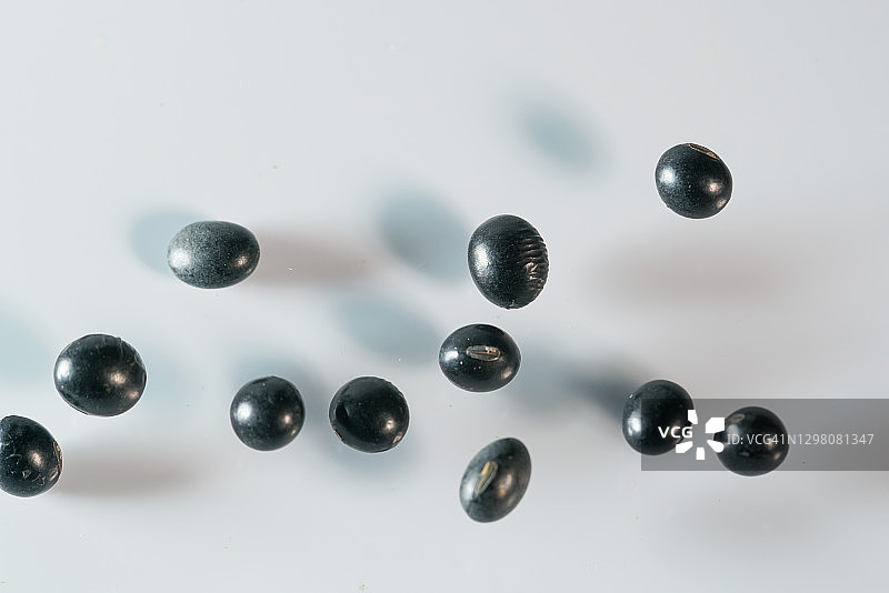 白色背景中半空飞舞的黑色大豆图片素材