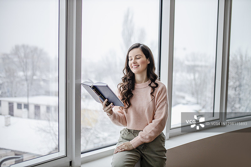 快乐的年轻女子在家放松和读书图片素材