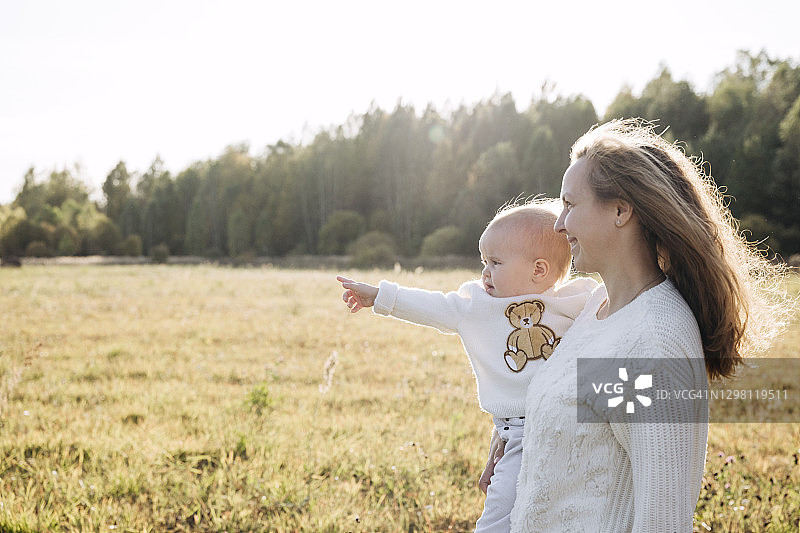 微笑的母亲抱着女婴站在农田里图片素材
