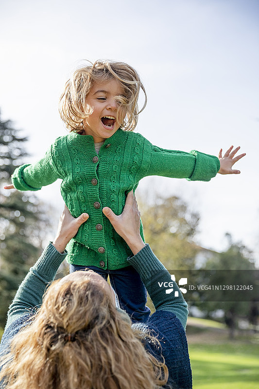 母亲在公园玩耍时抱起女儿图片素材