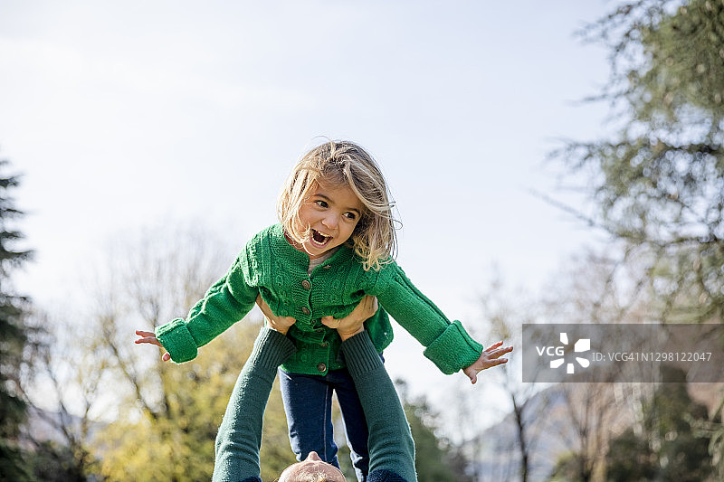 在公园玩耍时，母亲抱起快乐的女儿图片素材