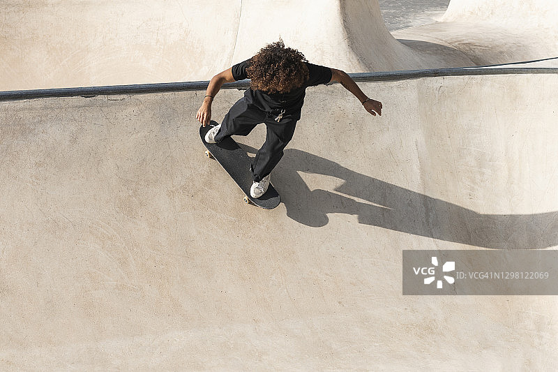 卷发运动员在滑板公园练习滑板图片素材