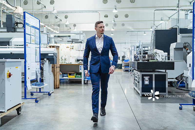 穿西装的商务男人在工厂里行走图片素材