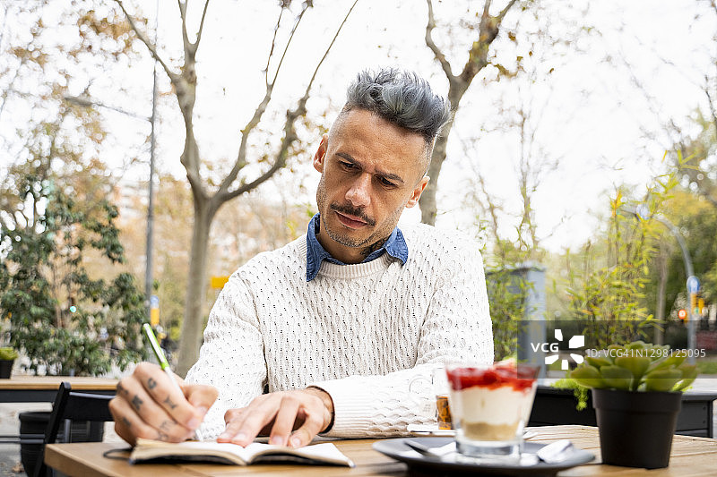 男人在咖啡馆专注地读书写作图片素材