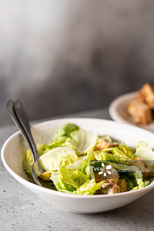 健康凯撒沙拉：新鲜蔬菜和面包丁，灰色桌面图片素材