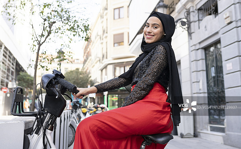 戴头巾骑共享单车的年轻女子肖像图片素材