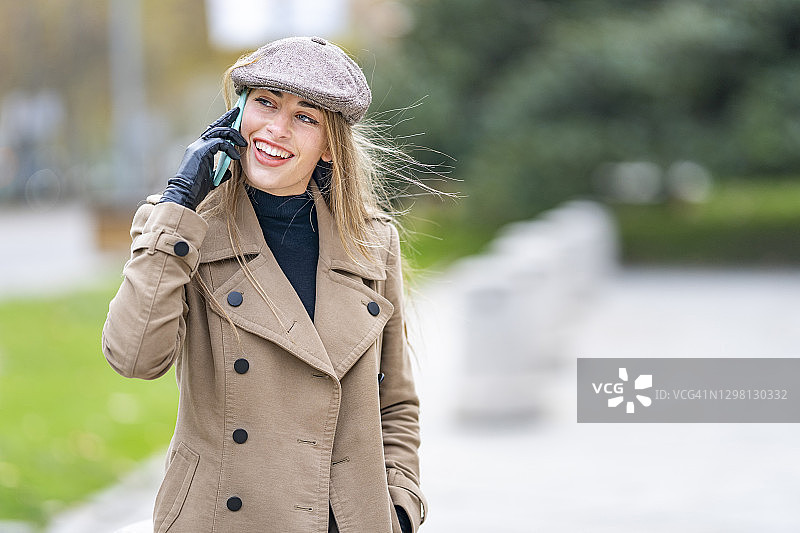 在公园里用智能手机聊天的快乐女人图片素材