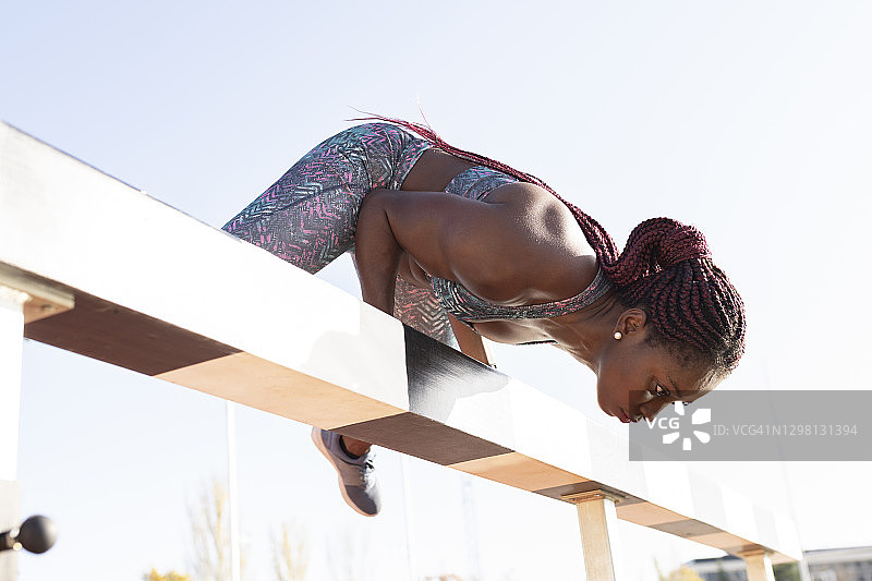 晴朗蓝天下，在平衡木上进行平衡运动的辫发女运动员图片素材