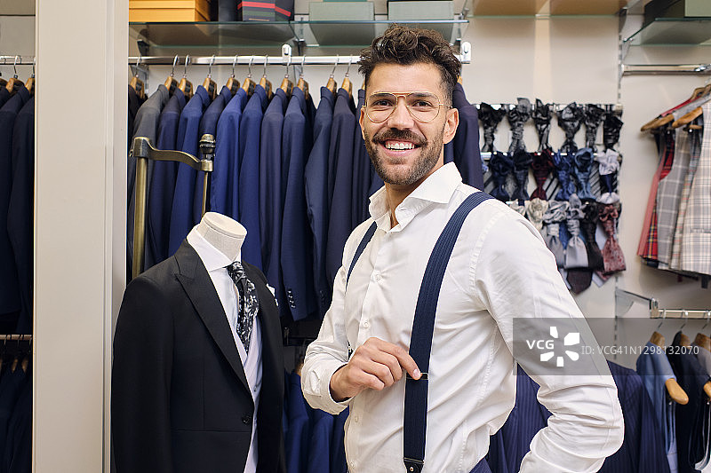 在裁缝精品店里穿着白色衬衫和蓝色吊带的微笑男人肖像图片素材