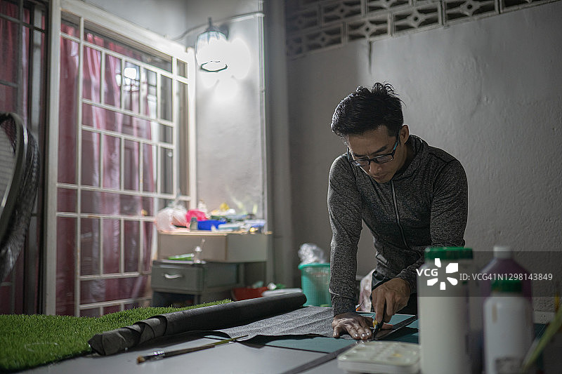 华人中年男人在家工作至深夜，正在裁剪皮革图片素材