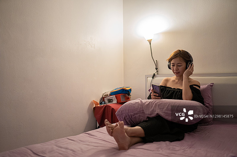 亚裔女人睡前在床上使用智能手机图片素材