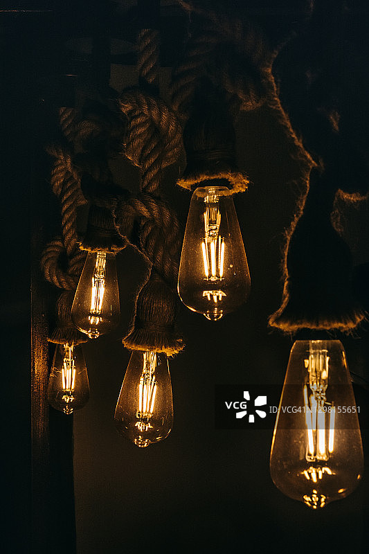 黑暗中发光的复古爱迪生灯泡，用绳子装饰的现代设计图片素材