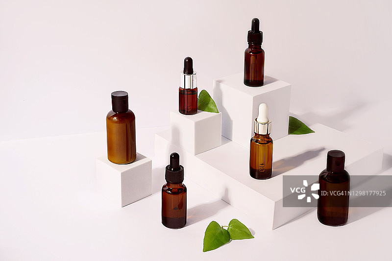 白色背景展台上用于按摩油、面部精华液、身体乳的各类瓶子图片素材