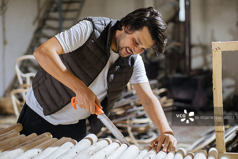 英俊的工匠在工作场所拿着锯子和木板图片素材