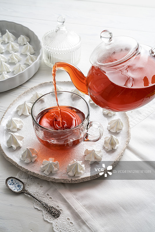 下午茶时间的红色茶，茶壶倒在杯子里，配蛋白酥图片素材