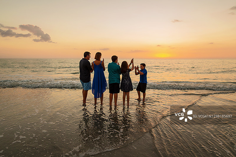 一家五口站在海边观看日落图片素材
