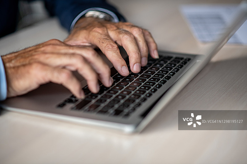 特写：老年男人在笔记本电脑上打字图片素材