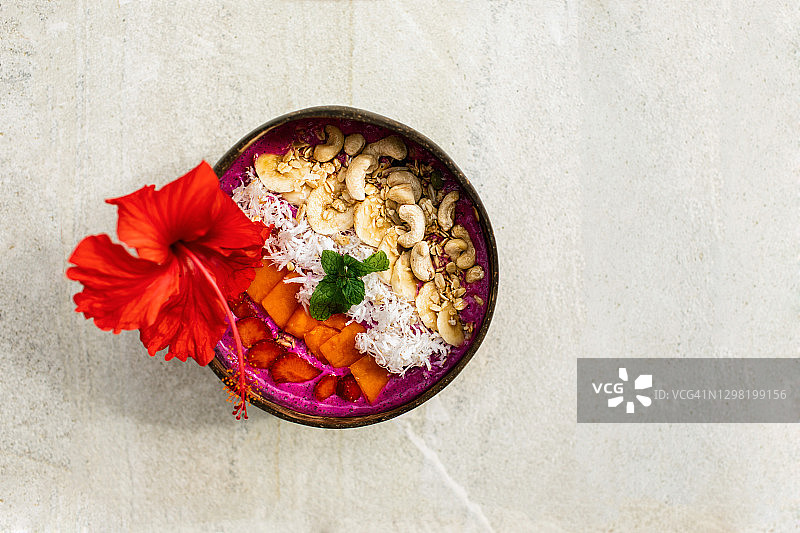 新鲜热带有机水果冰沙，椰子碗配吸管，亚洲度假村泳池边的夏日草帽。火龙果和香蕉纯素碗，配木瓜、谷物坚果和种子。夏日氛围。图片素材