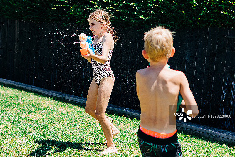 在后院玩水枪的男孩和女孩图片素材
