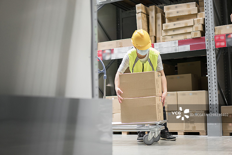 戴安全帽的工人在仓库中搬运货物图片素材
