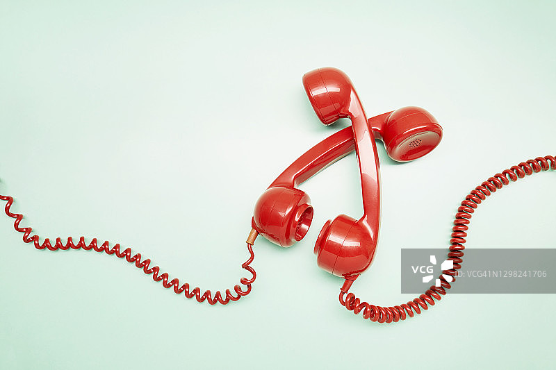 俯视：两个红色老式电话听筒在绿松石背景上图片素材