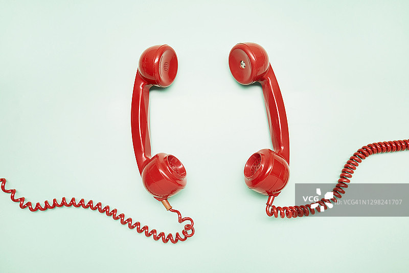 俯视：两个红色老式电话听筒在绿松石背景上图片素材