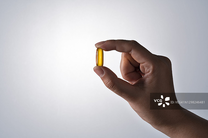 手持黄色软胶囊图片素材
