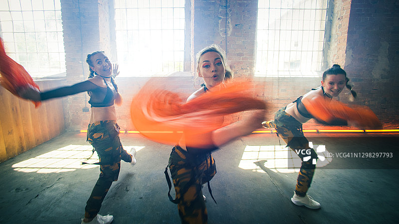 在工作室跳舞的女舞者，橙色头巾和迷彩服的舞蹈编排图片素材