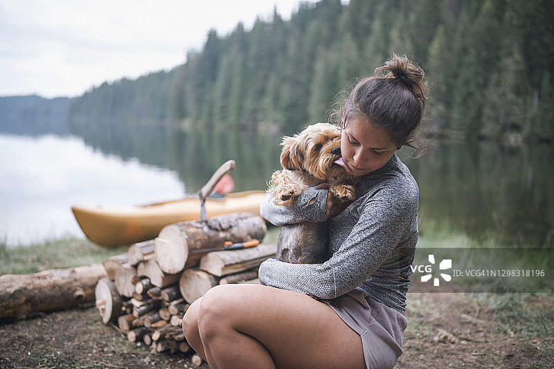 年轻女孩在露营时和她的狗拥抱玩耍图片素材