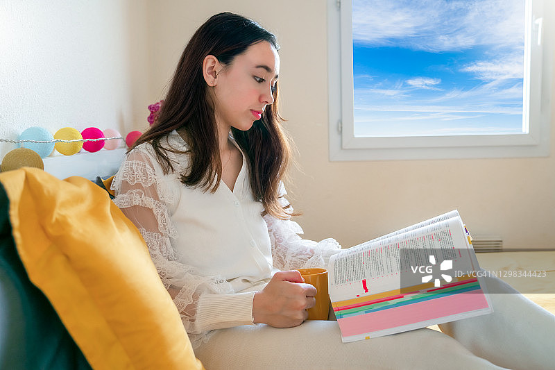 自学概念。年轻女子坐在家里地板上看书。图片素材