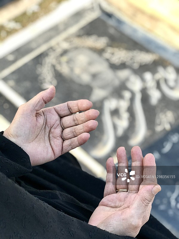 在伊朗德黑兰的公共墓地，一名妇女为因新冠病毒去世的丈夫祈祷图片素材