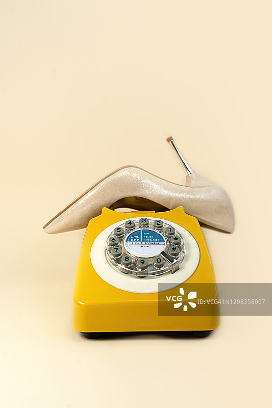 米色背景上，像老式电话听筒的金色时尚鞋图片素材