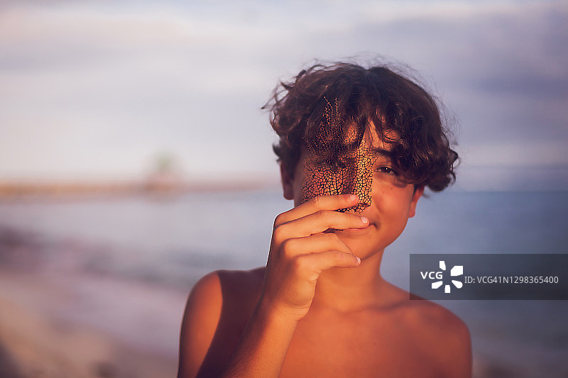 微笑的青少年男孩在热带海滩上拿着珊瑚图片素材
