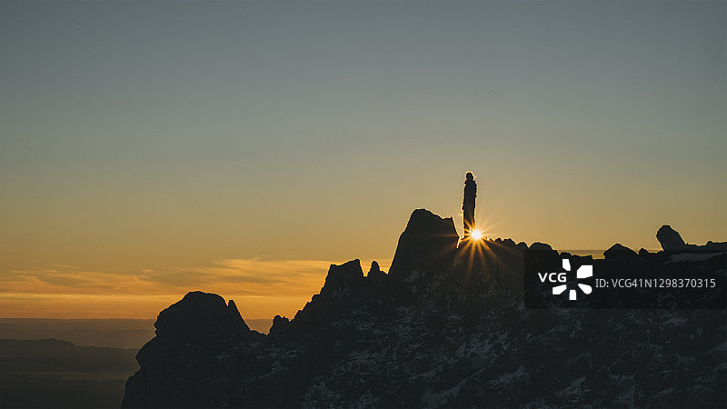 年轻女子站在新西兰汤加里罗的岩石顶端，远眺日落图片素材