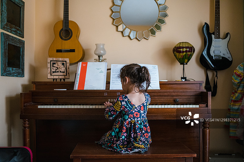 女孩弹钢琴，可爱的孩子在幼儿园练习乐器图片素材
