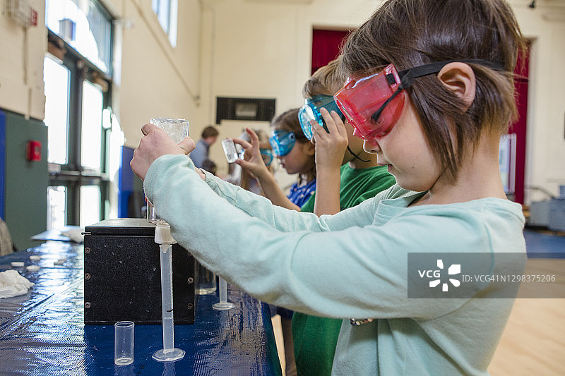 戴着安全眼镜的小女孩将液体倒入试管图片素材
