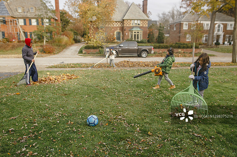 秋天，三个孩子帮父亲清理院子里的落叶图片素材