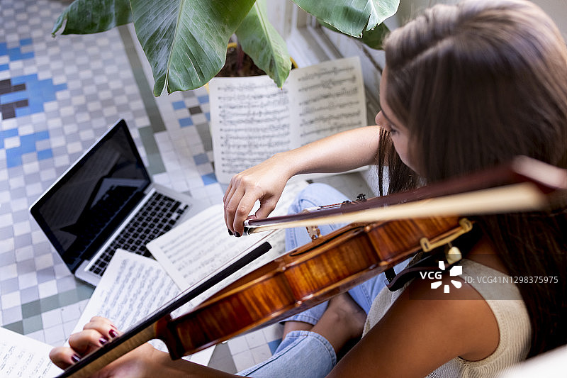 女音乐家用中提琴演奏，笔记本电脑放在地板上图片素材