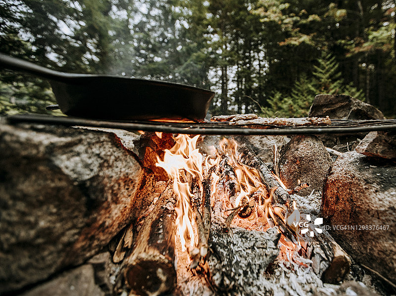 缅因州树林中营火煤炭上烹饪的铸铁锅图片素材