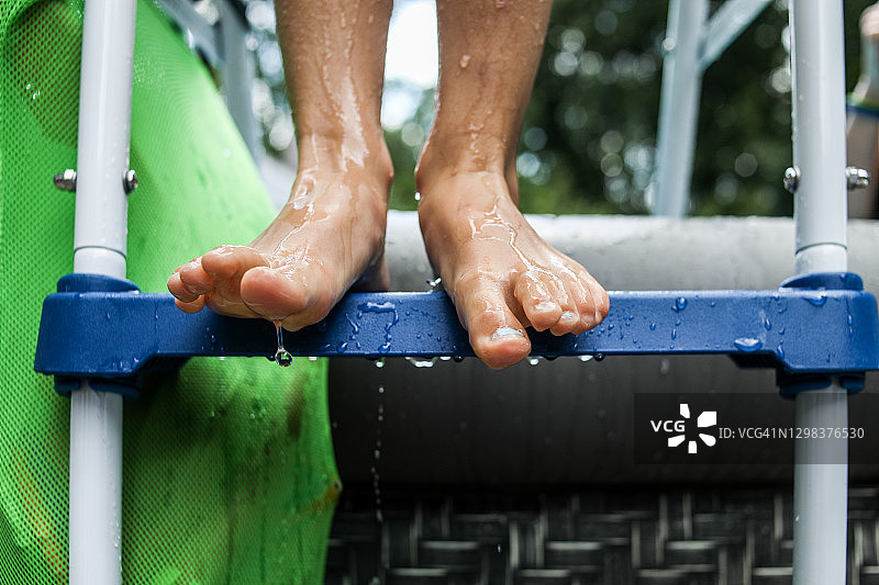 站在泳池扶梯上的湿脚特写，水滴滴落图片素材