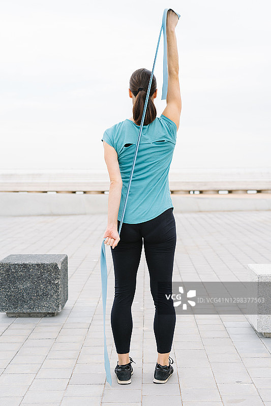 女孩在街上用弹力带手臂练习瑜伽图片素材
