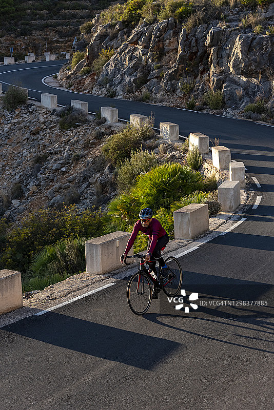 男子骑自行车行驶在贝尼萨至皮诺斯山路上图片素材