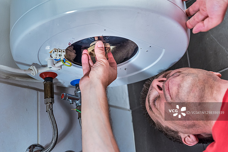 在浴室修理电锅炉的男人图片素材