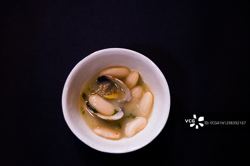 黑背景碗里的蛤蜊蚕豆图片素材