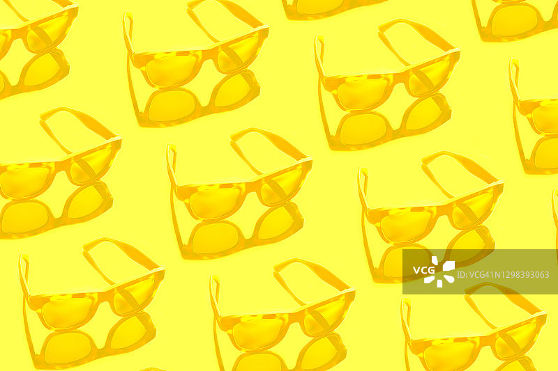阳光明媚的黄色背景上的黄色太阳镜与阴影，2021年流行色图片素材