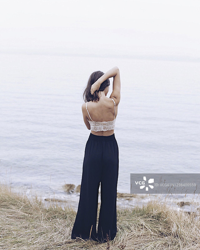 在海滩上伸展手臂的年轻女子背影图片素材