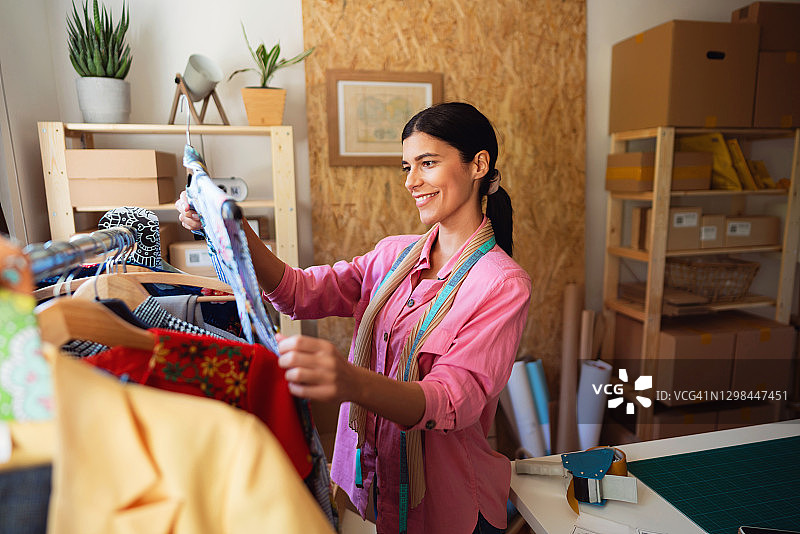 年轻女服装设计师拿着连衣裙准备新的在线订单图片素材